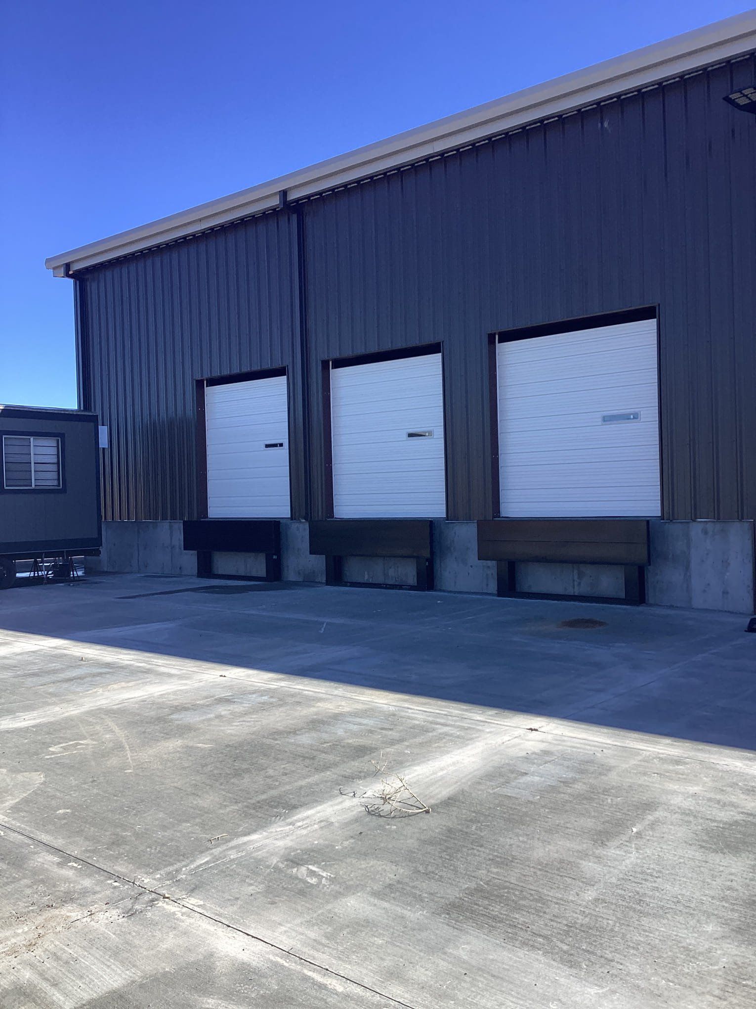 A warehouse with a lot of loading doors and a truck parked in front of it.