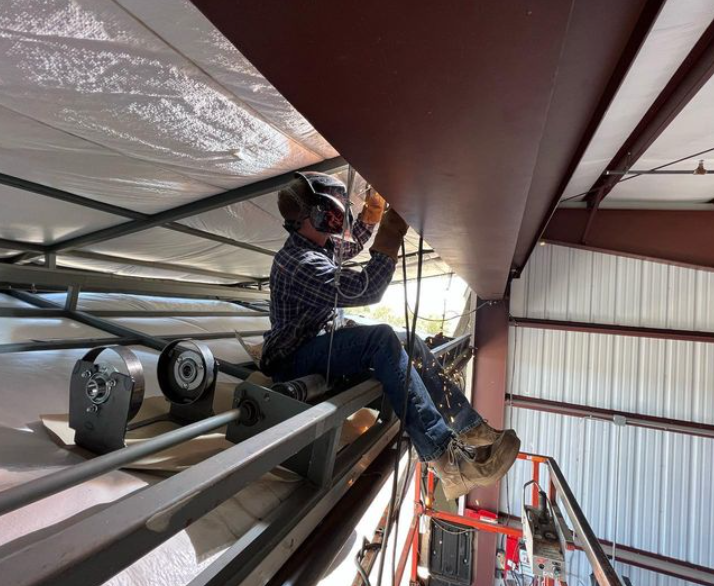 A man is welding a metal structure in a building.