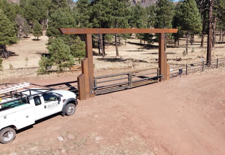 A white truck is parked in front of a wooden gate.