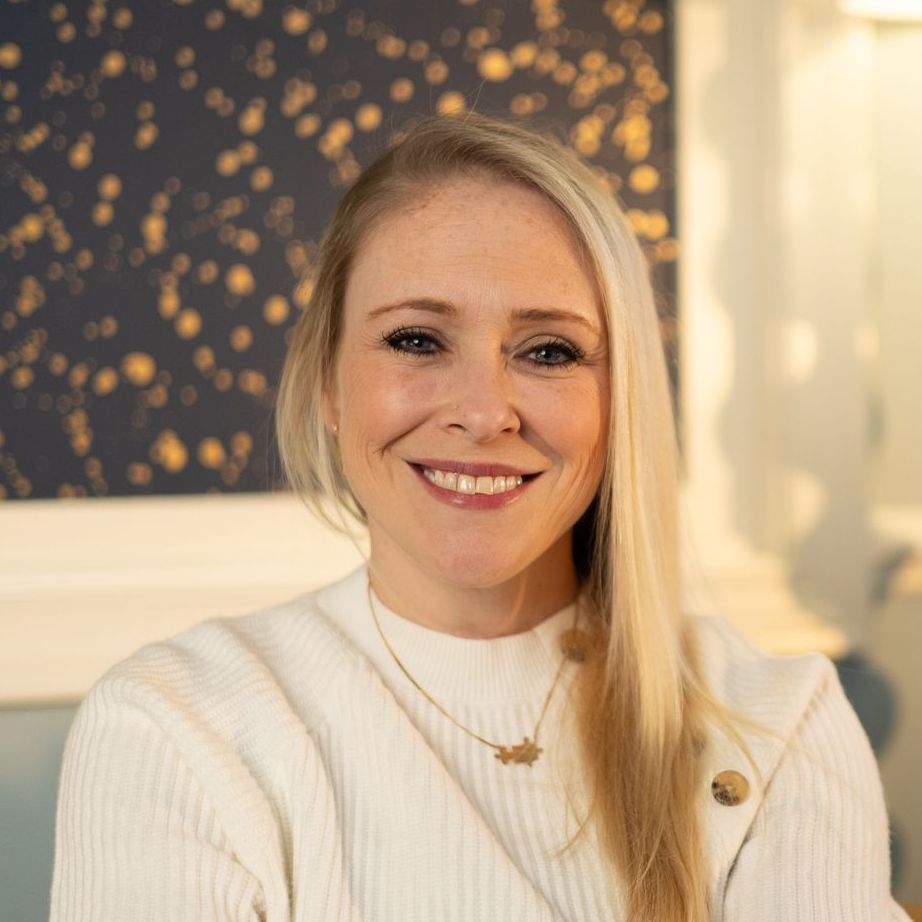 A woman with long blonde hair is smiling for the camera.