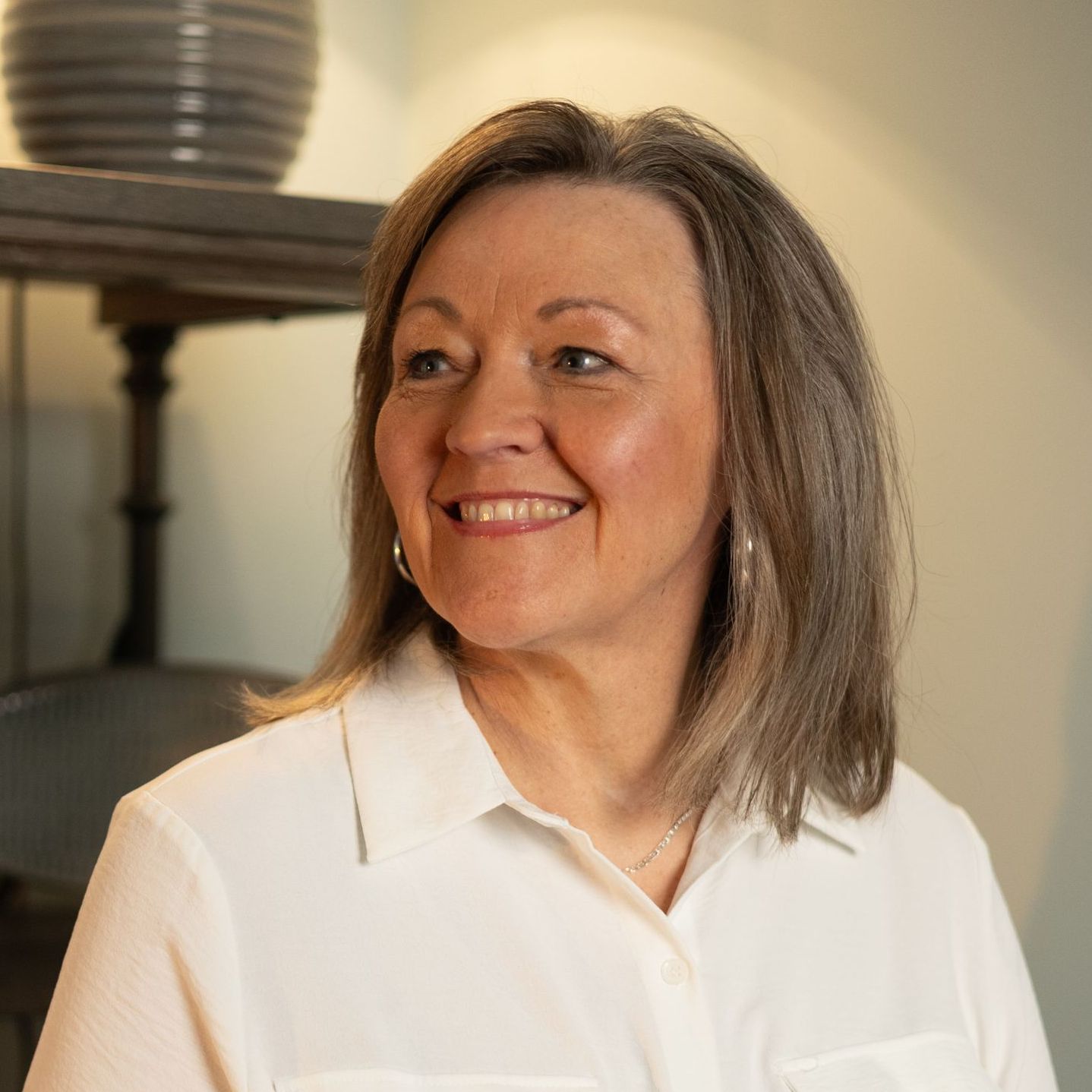 A woman is smiling in front of a tree.
