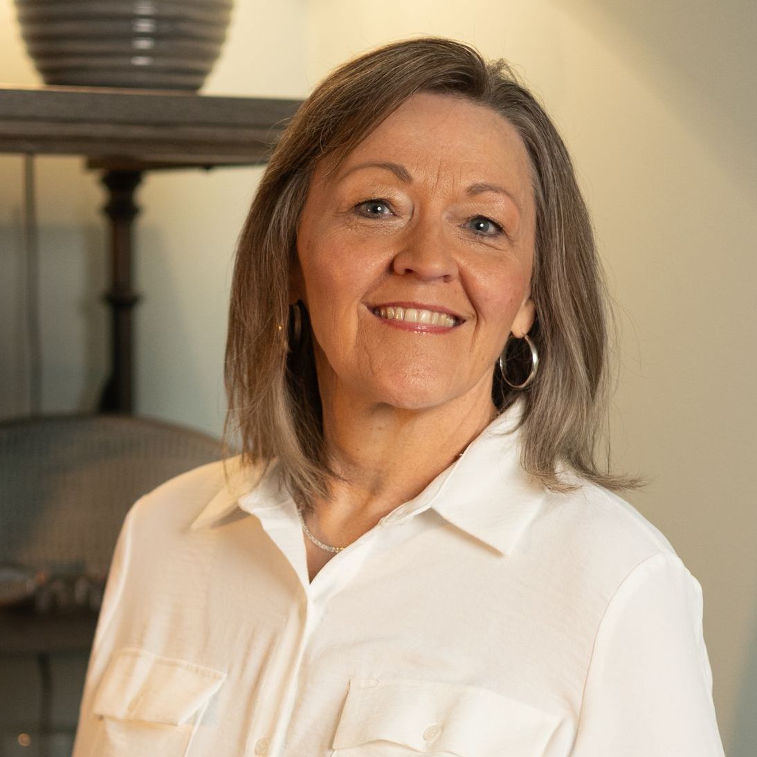 A woman is smiling in front of a tree.