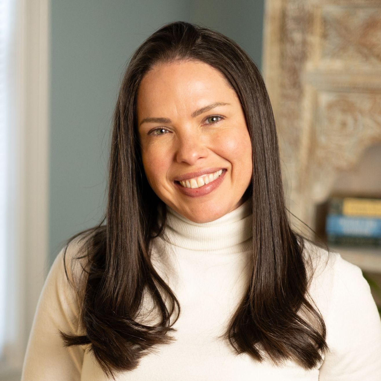 A woman in a black turtleneck is smiling for the camera.