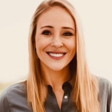 A woman with long blonde hair is smiling for the camera.