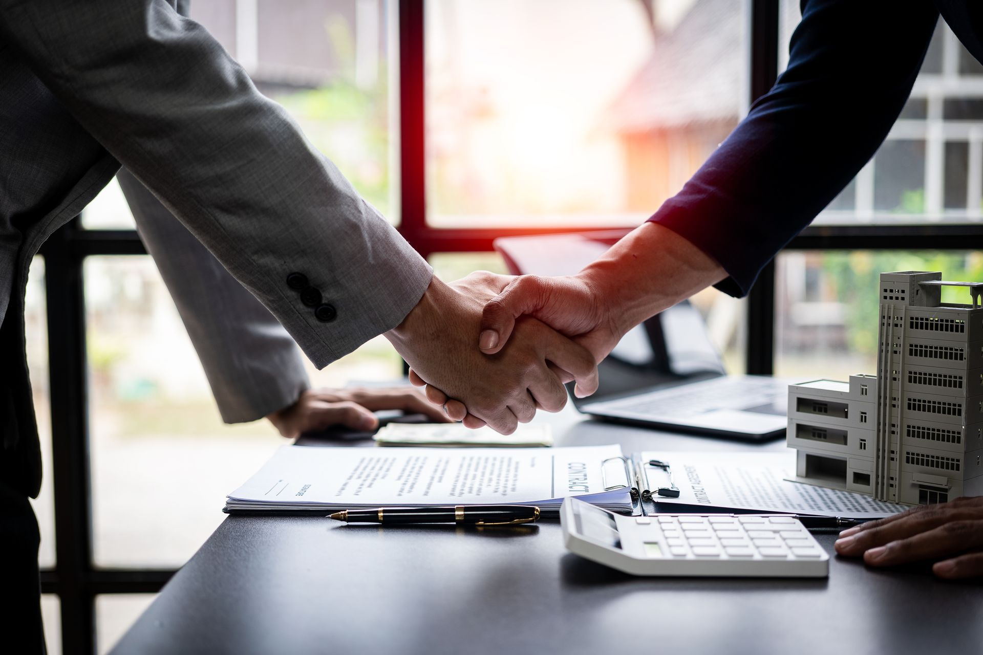 A lawyer and a client shaking hands over an office table after a real estate agreement.