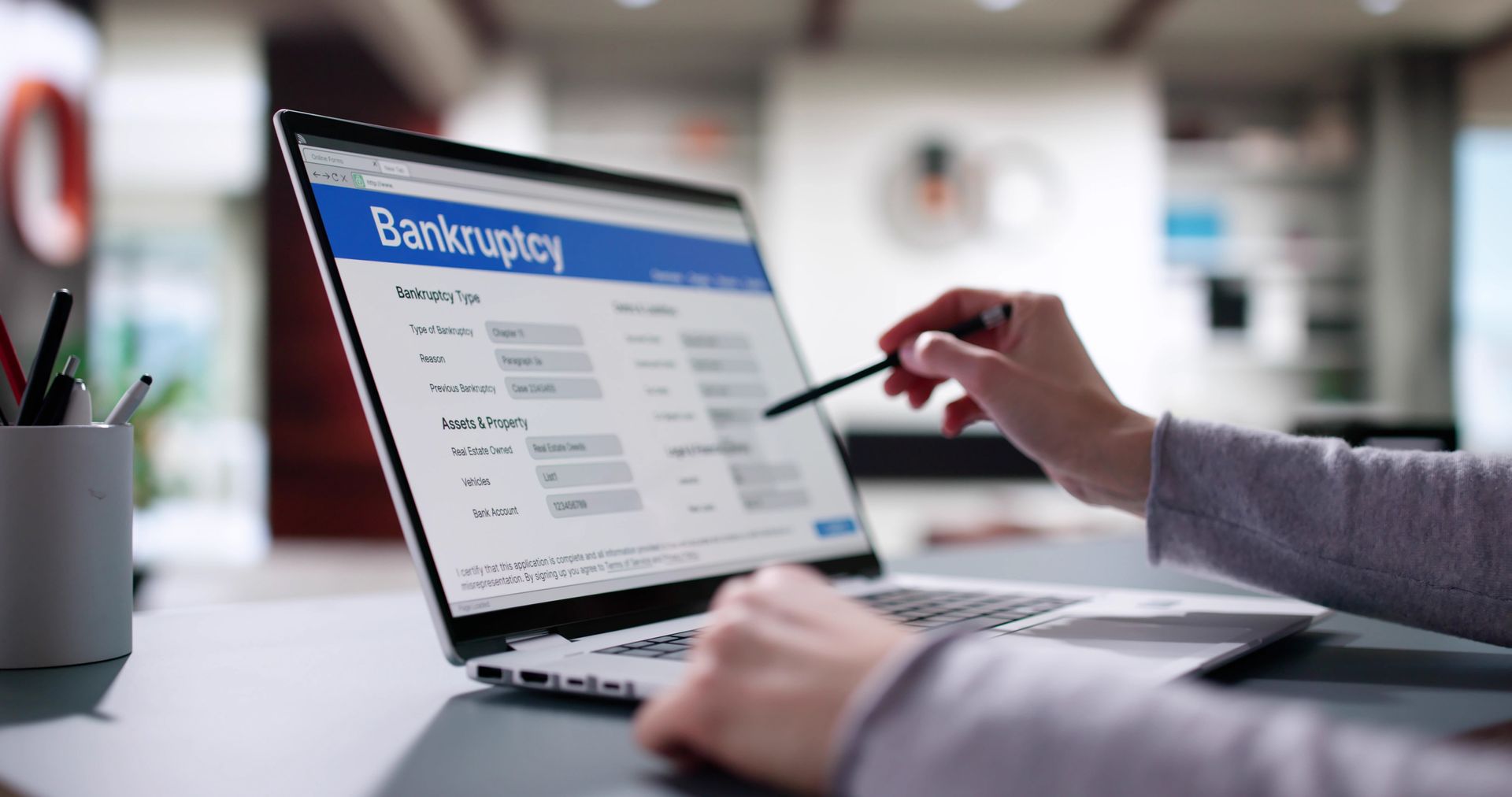 Bankruptcy attorney reviewing financial documents on laptop with bankruptcy form displayed.