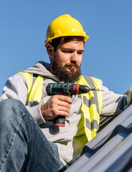 Roofing technician using a cordless drill to install metal roof panels in Atlanta, Georgia.