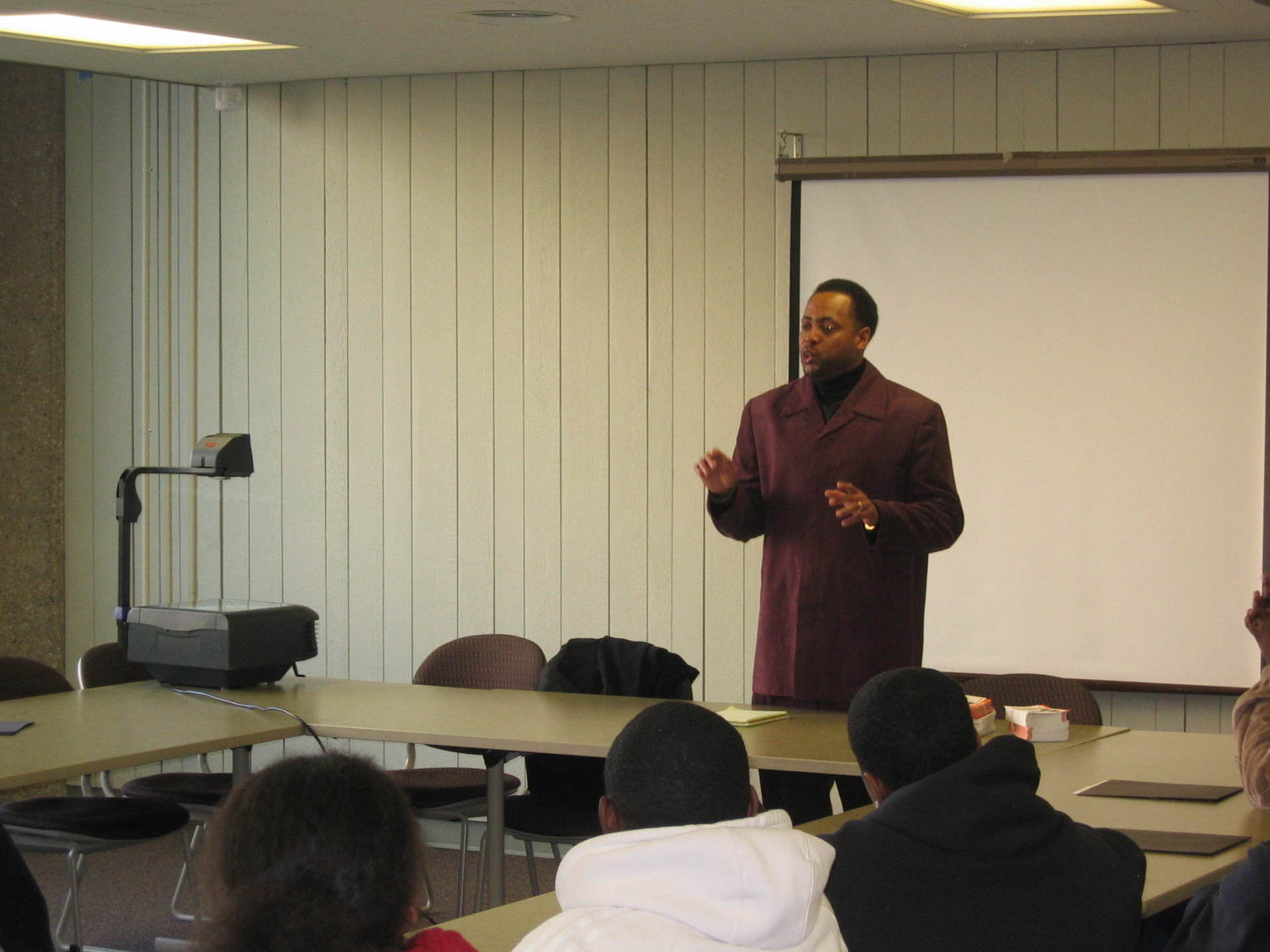 Male speaker standing and speaking to room filled with students at previous Positive Images Leadership Teen Summit meeting in Milwaukee