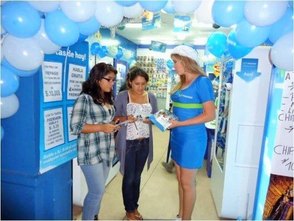 Una mujer con un vestido azul está hablando con dos mujeres en una tienda.