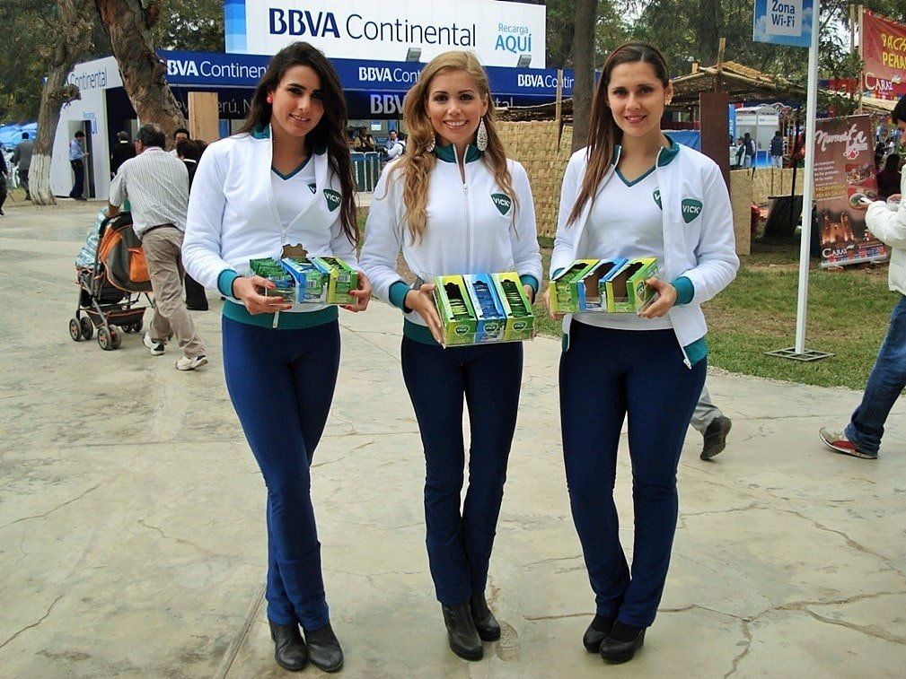 Tres mujeres de pie delante de un cartel del BBVA Continental