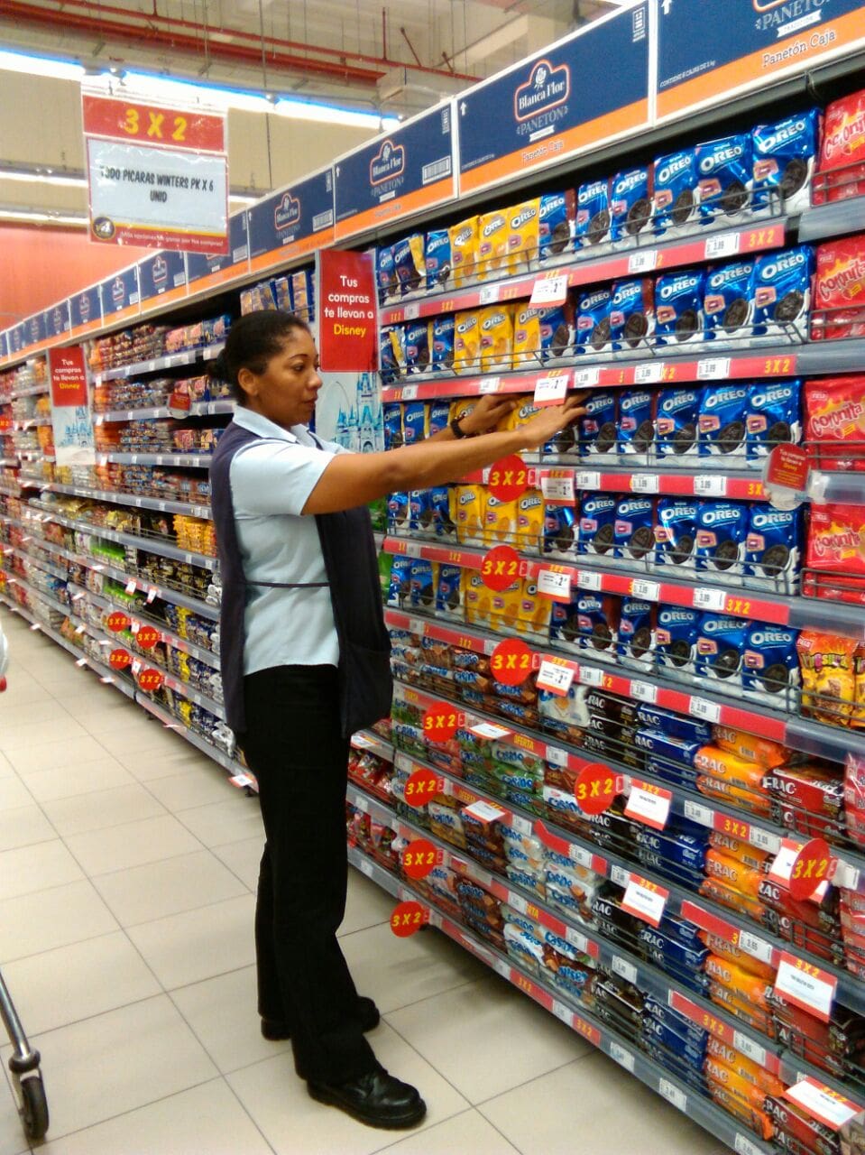 Una mujer está parada en una tienda de comestibles mirando galletas Oreo.