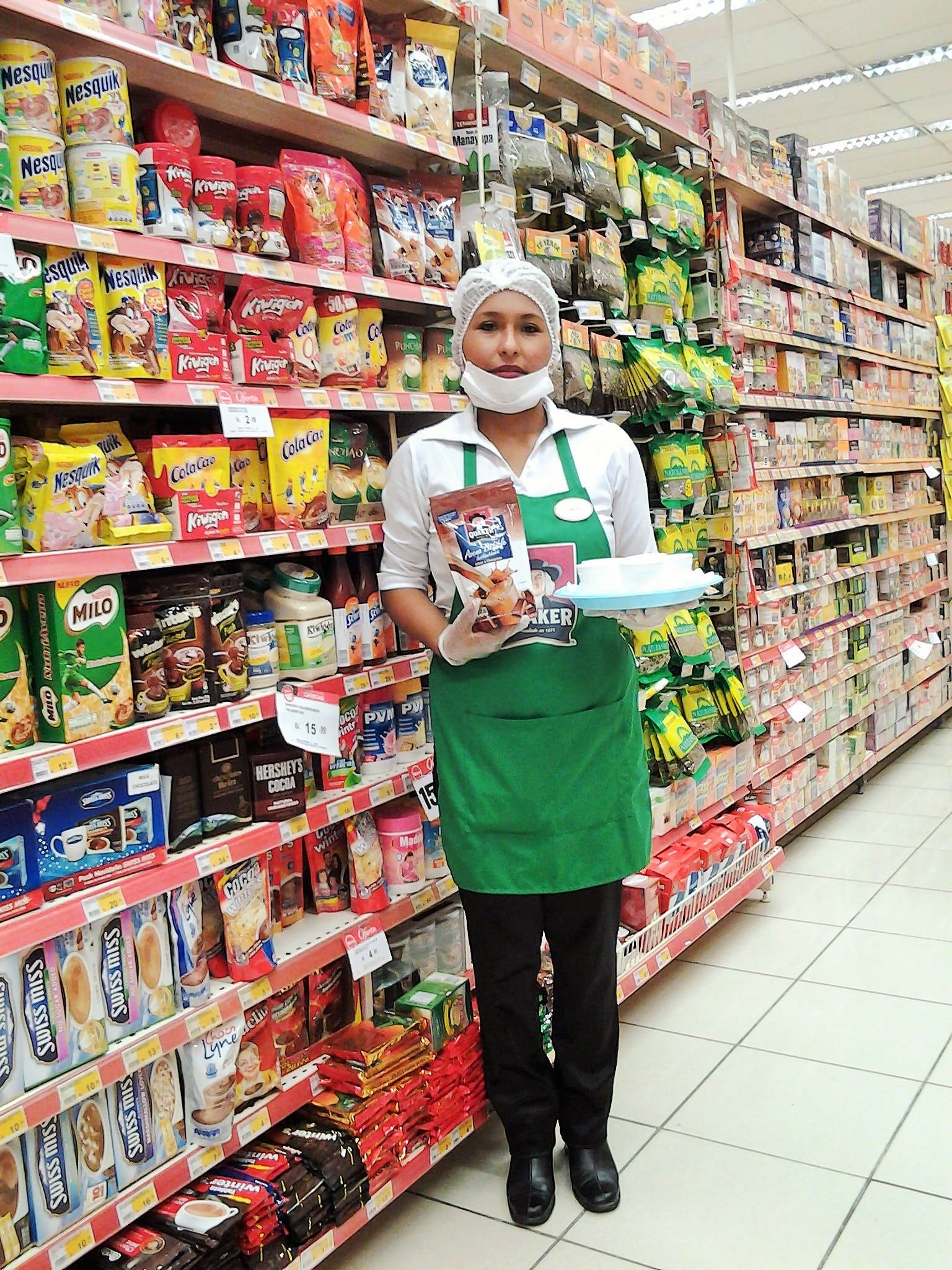Una mujer está parada en una tienda de comestibles sosteniendo una bandeja de comida.