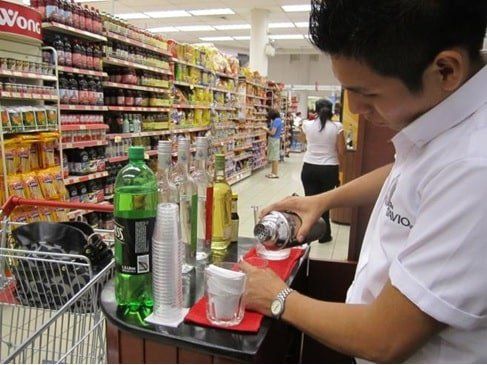 Un hombre con camisa blanca vierte líquido en un vaso.