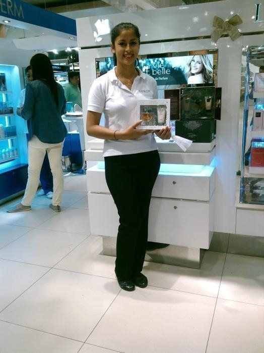 Una mujer con una camisa blanca sostiene una caja en una tienda.