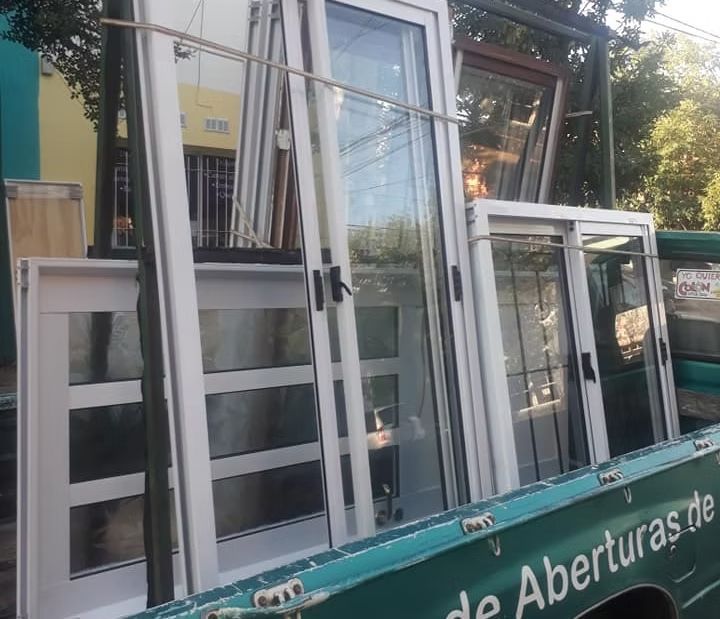 Trabajador midiendo un marco de ventana blanco dentro de una habitación parcialmente renovada.