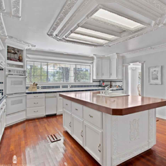 A kitchen with white cabinets and a large island in the middle