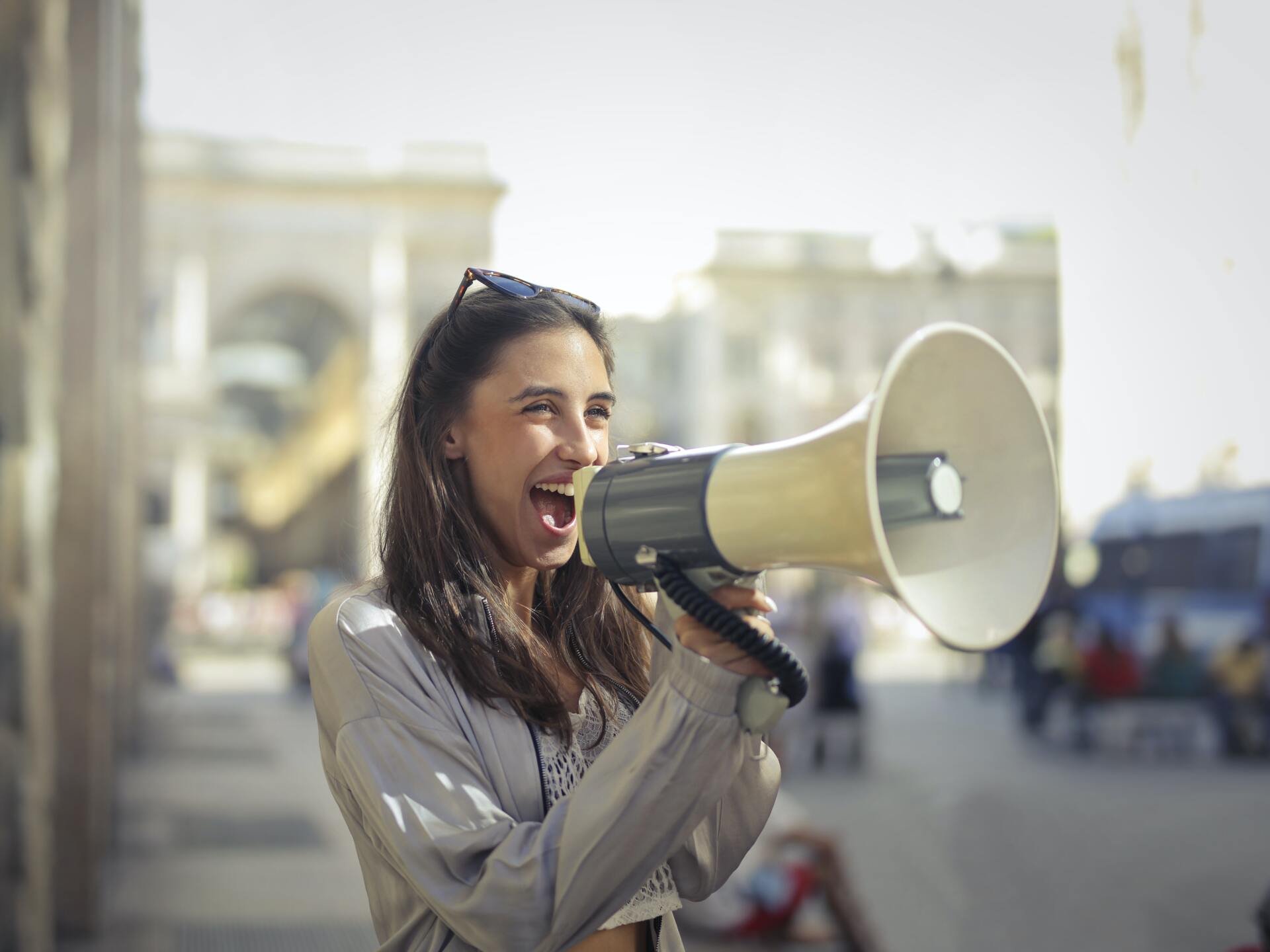 A girl smiling, shouting and holding  a megaphone.