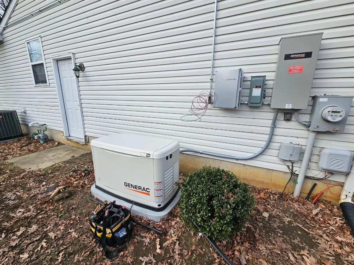 A residential gas-powered generator installed outdoors next to a house with electrical components.