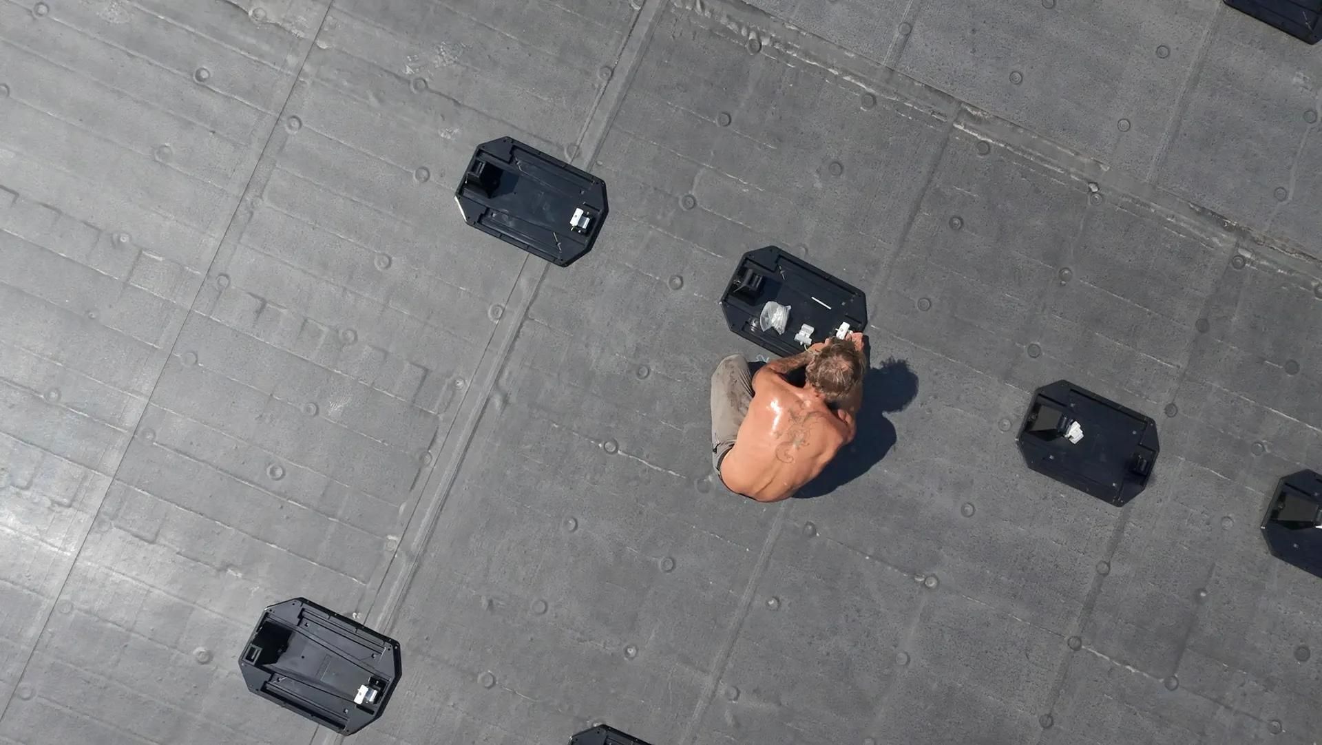 Person seated surrounded by rectangular black objects on a gray surface.