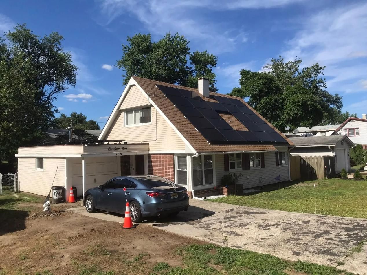 House with solar panels on the roof, car in the driveway, and garage. 