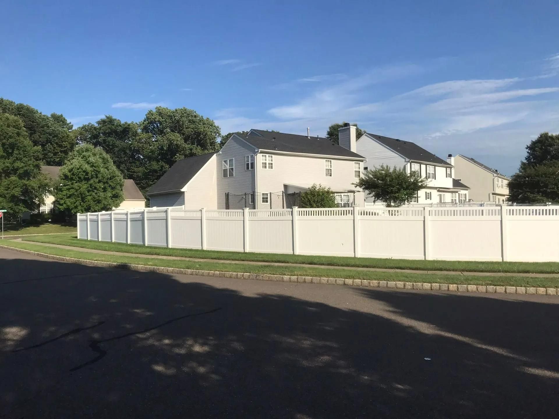 White fenced suburban homes under a blue sky.