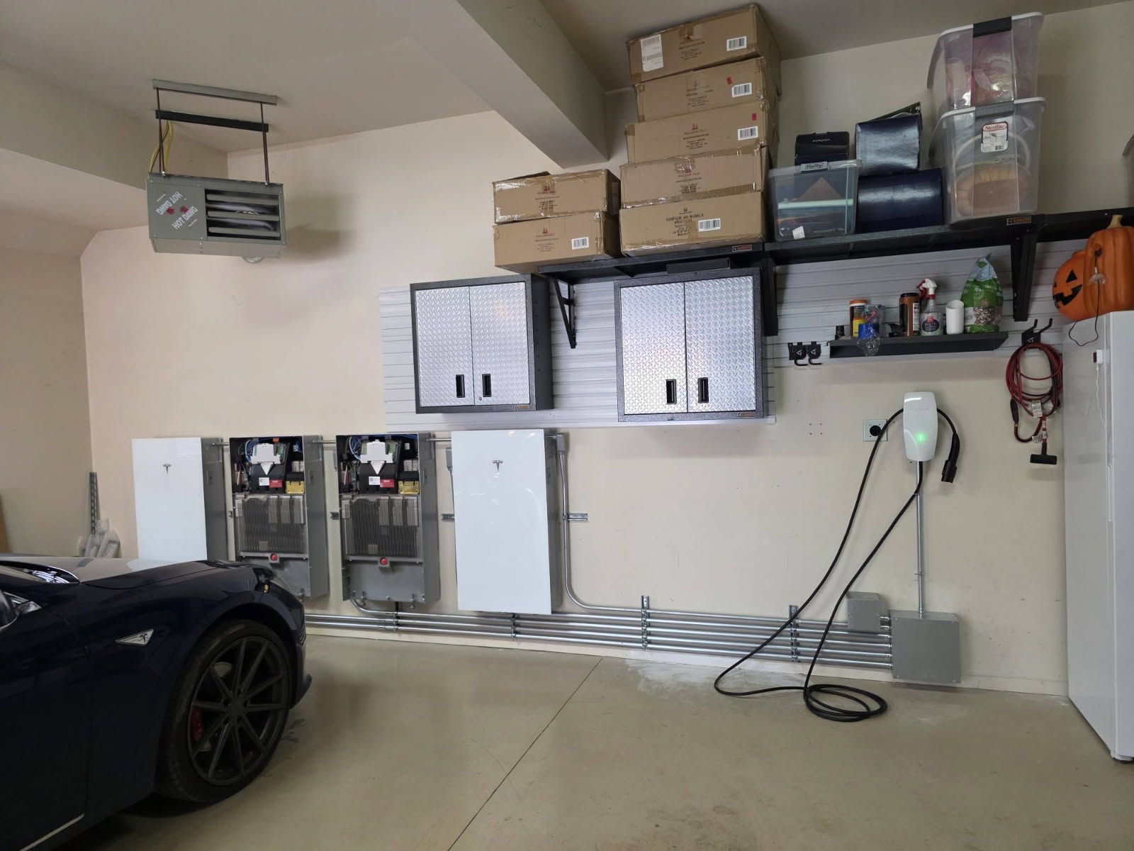 Gray car parked in front of a blue house with solar panels, American flag.