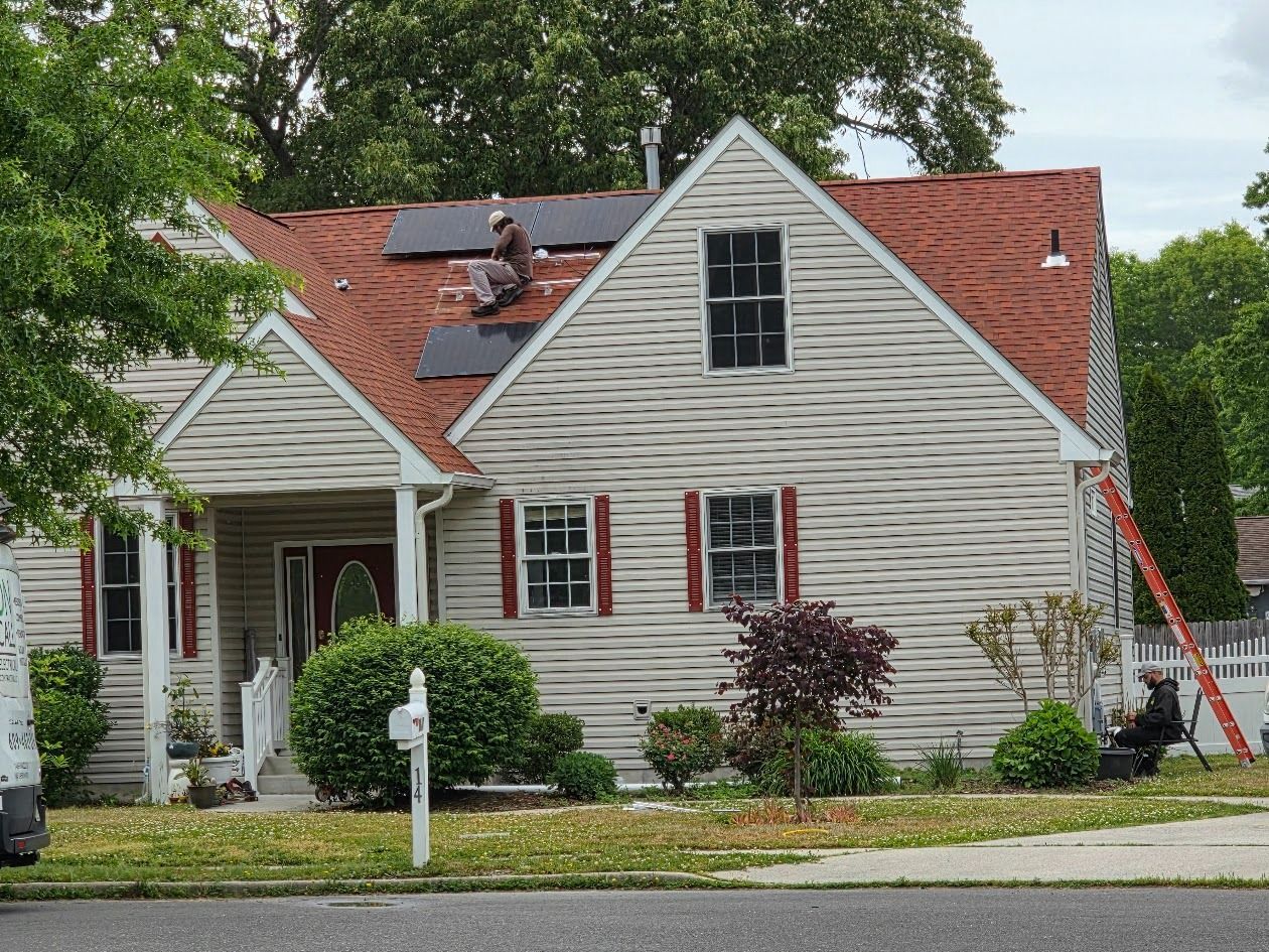 White house with black solar panels on the roof and black shutters.