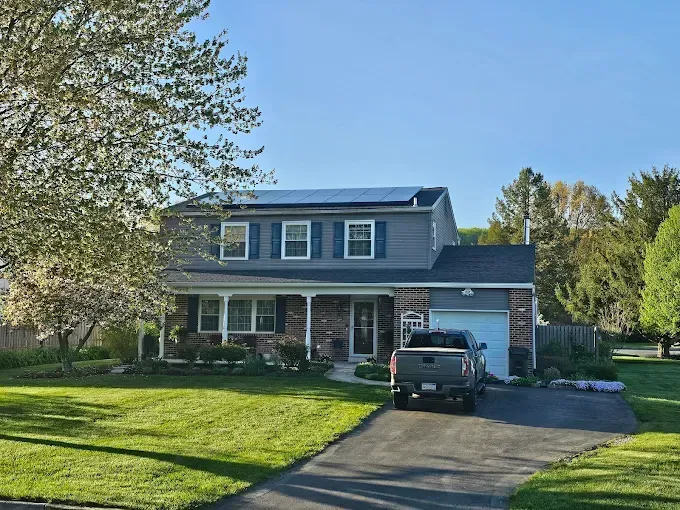 Two-story house with blue siding, solar panels, and a pickup truck parked in the driveway.