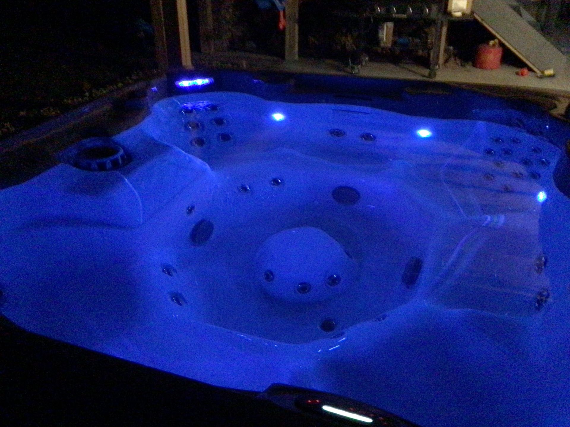 A hot tub is lit up with blue lights at night