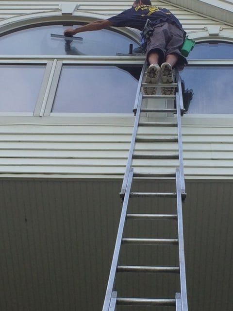 Best Window Cleaning Service — A Man Using A Squeegee in Bloomfield, MI