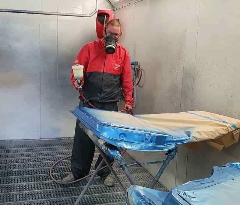 A Man Wearing a Gas Mask Is Spray Painting a Car — Andy's A1 Auto Care in Barrack Heights, NSW