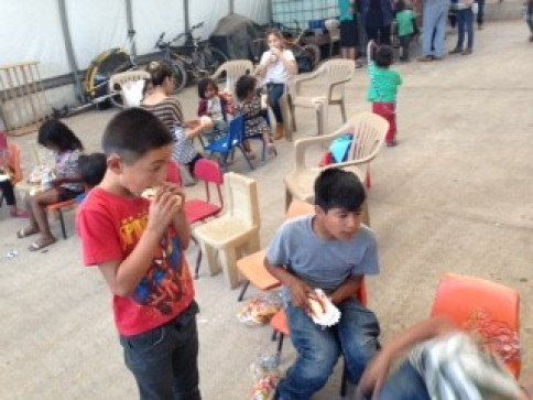 A boy in a spiderman shirt is eating a hot dog