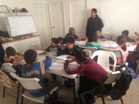 A group of children are sitting at tables in a classroom
