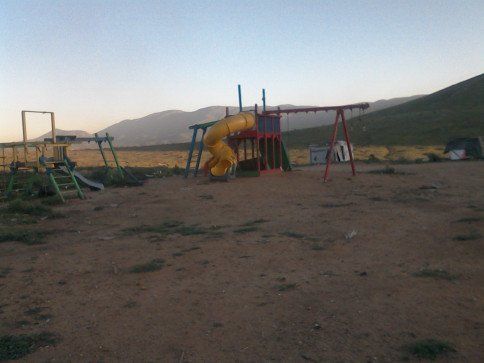 A playground with mountains in the background and a yellow slide