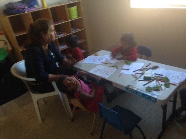 A woman sits at a table with three children
