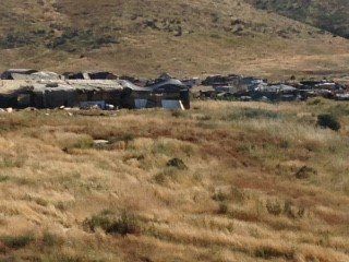 A group of cars are sitting in a field with mountains in the background.