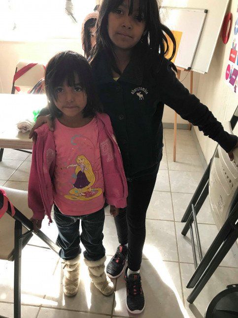 Two little girls standing next to each other in a room