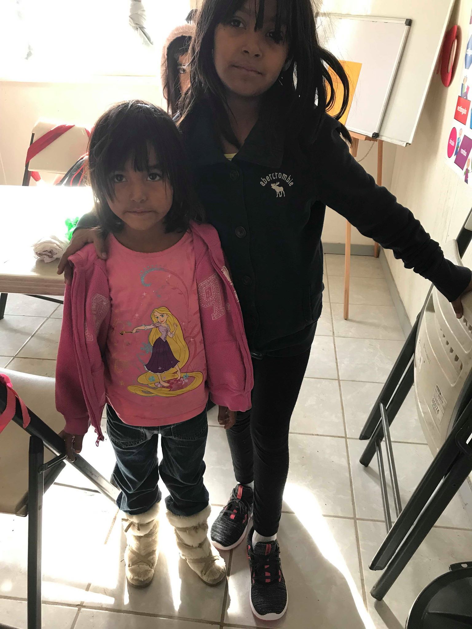 Two little girls are standing next to each other in a room.