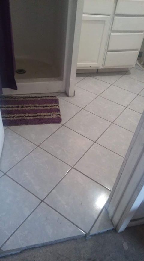 A bathroom with white tile floors and a purple rug on the floor.
