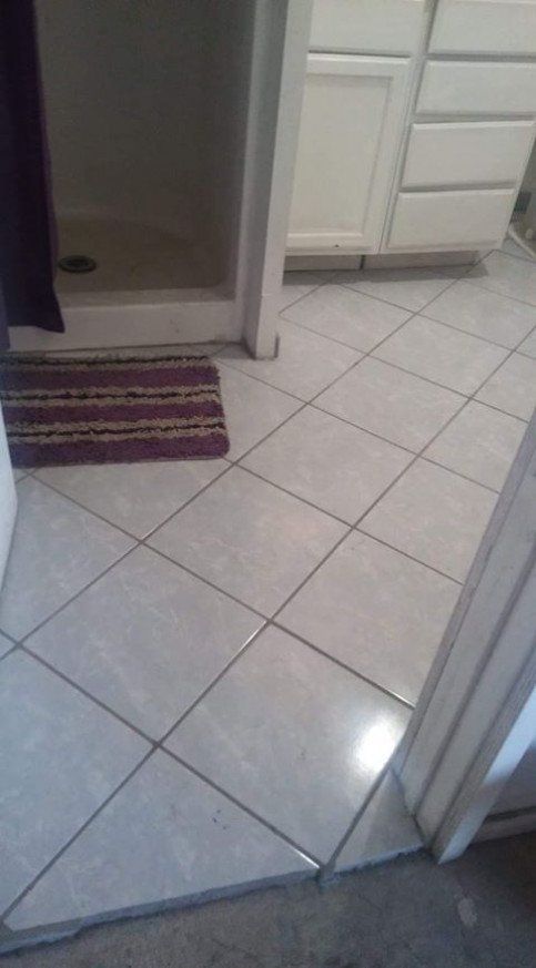 A bathroom with a tiled floor and a shower stall.