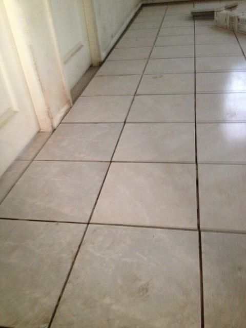 A tiled floor in a kitchen with white cabinets.
