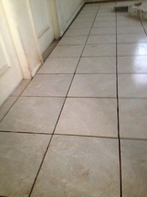 A tiled floor in a kitchen with white cabinets.