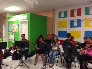 A group of people are playing violins in a room.