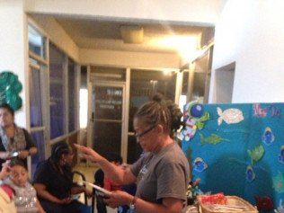 A woman is reading a book to a group of people in a room.