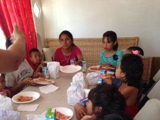 A group of children are sitting at a table eating pizza.