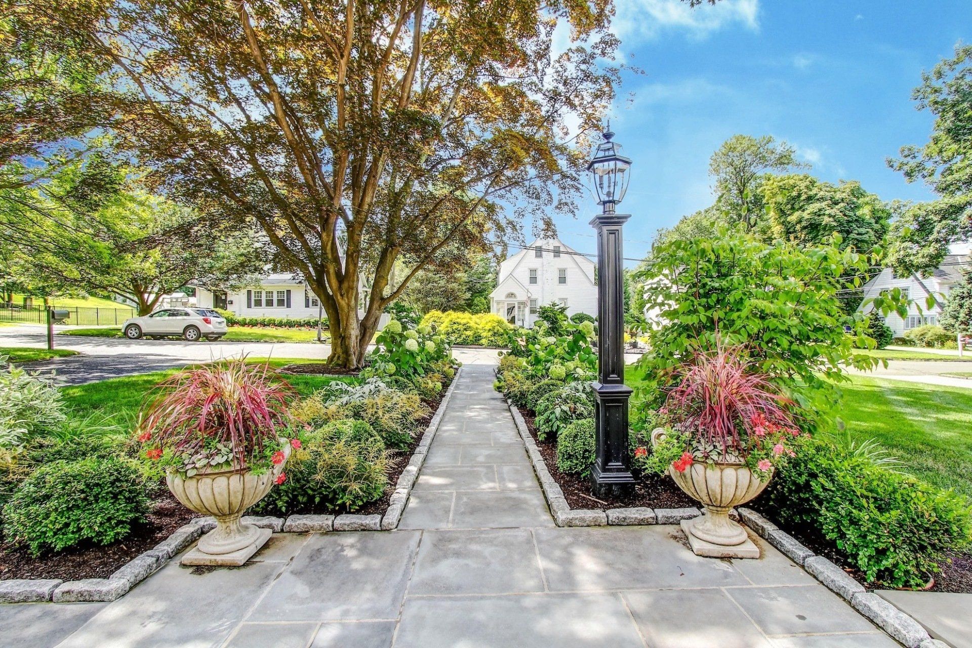 a stone walkway surrounded by flowers and trees in a park .