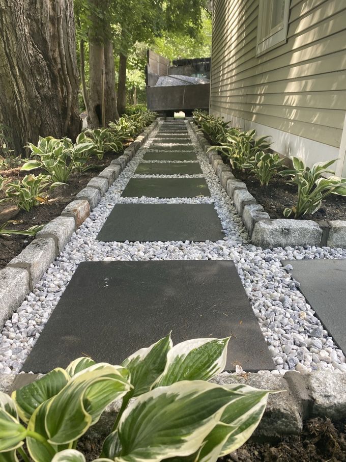 a walkway leading to a house surrounded by plants and gravel .