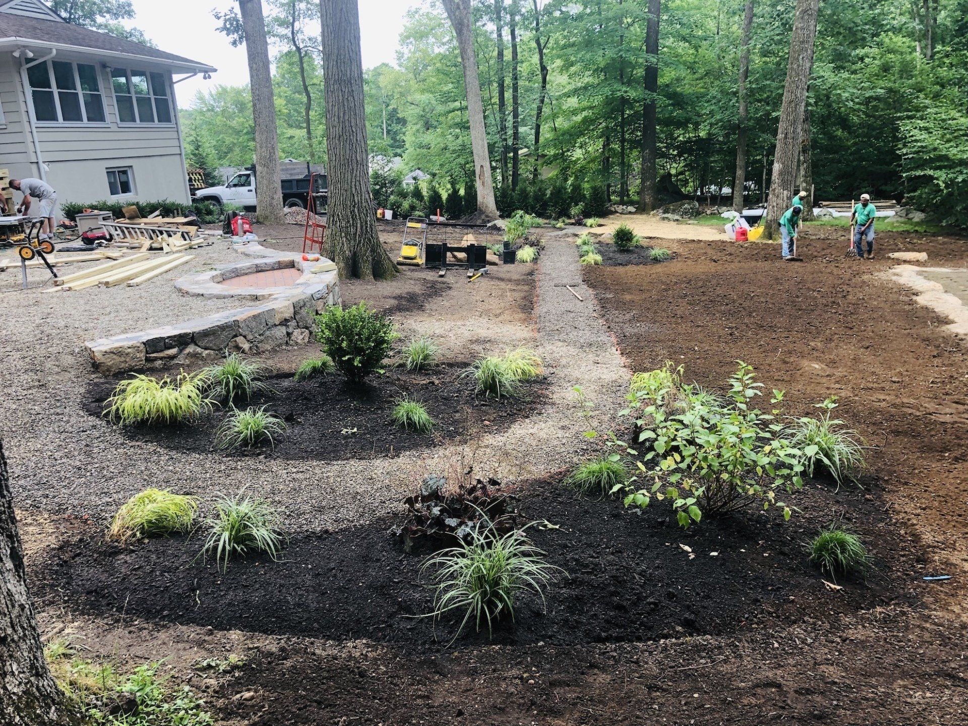 a group of people are working on a lush green lawn in front of a house .