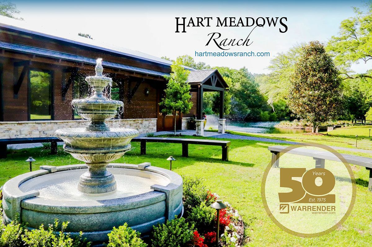 A fountain in front of a building that says hart meadows ranch