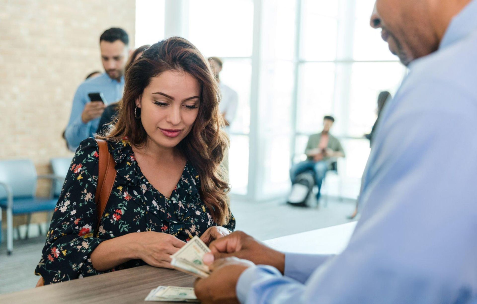 A woman is receiving money from a man behind a counter. A woman is receiving money from a man behind a counter.